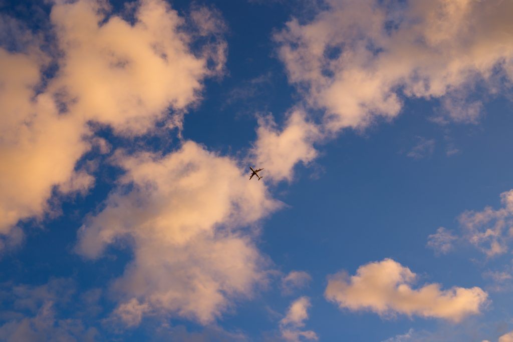 Photo by Jason Ortego on Unsplash. Plane, fly over, clouds, sky