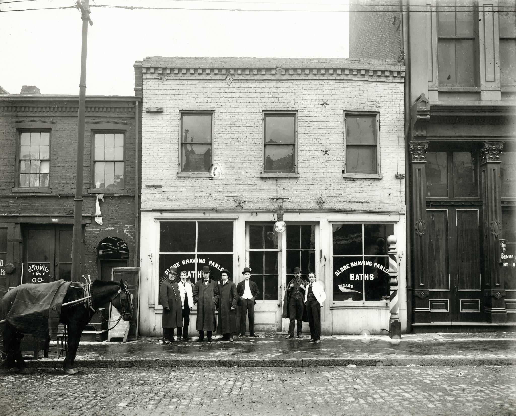 Group of men standing in front of the Globe Shaving Parlor at 1015 Carr. Photograph, ca. 1910. In the surrounding blocks lived Italians, Yiddish-speaking Russians and Hungarians, and African American families from the South.