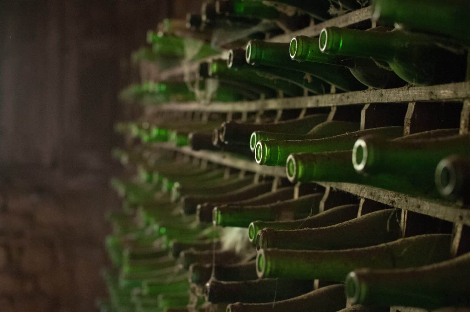Empty green bottles on a rack.
