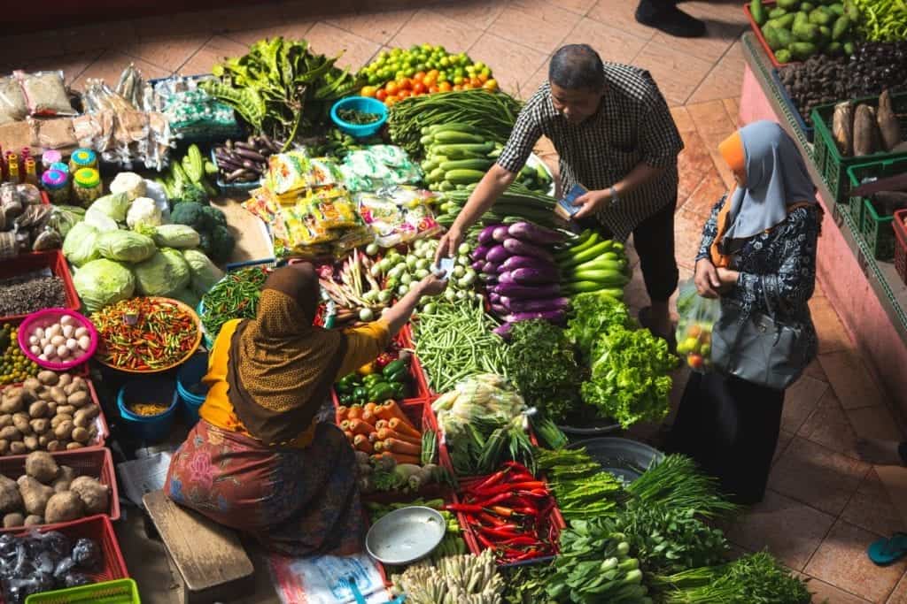 People at a market buying vegetables