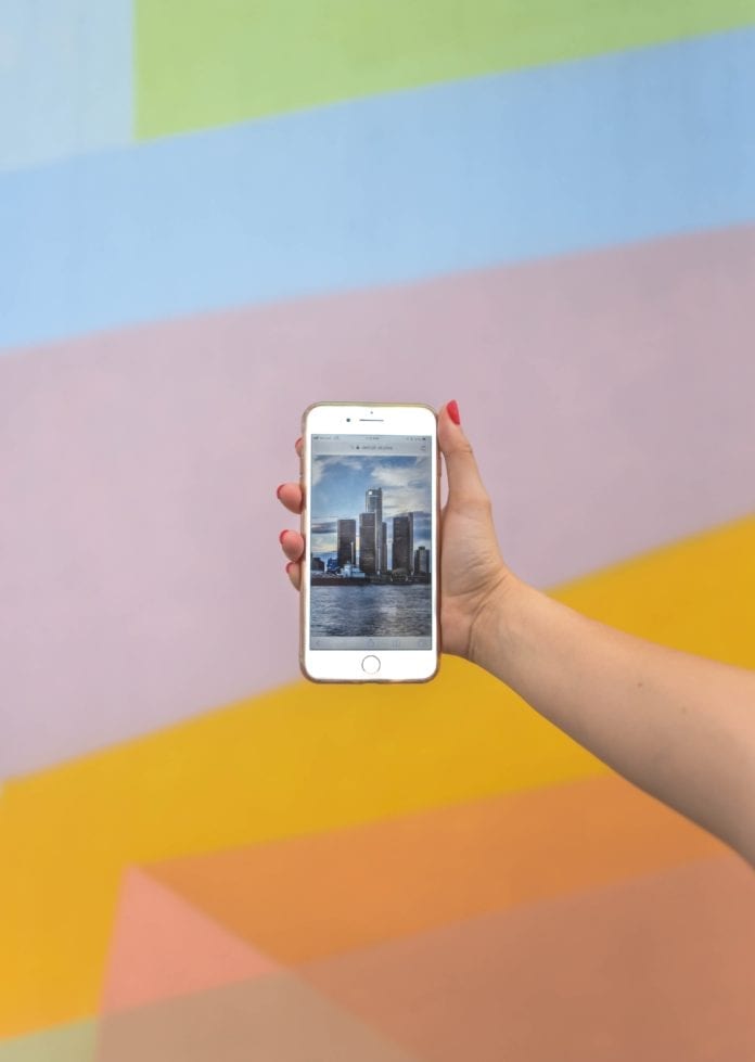 A person holding a phone in front of a colorful background.