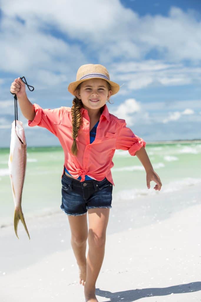 Kid on the beach with a fish.
