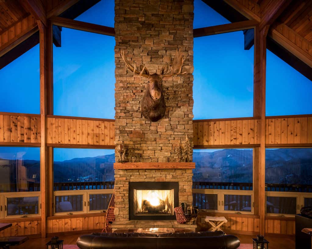 Large glass wall with a central stone fireplace, overlooking the North Carolina High Country in Boone