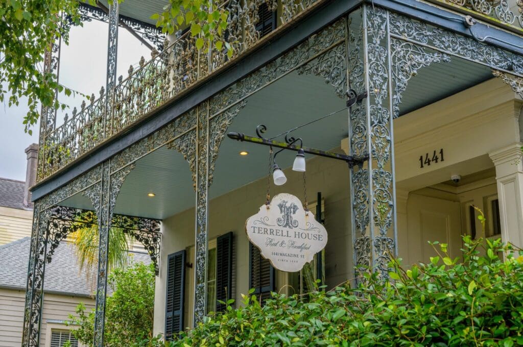A historic guest house with ornate ironwork on a two-story balcony. The sign reads Terrell House Bed & Breakfast with an address, surrounded by trees. The house number 1441 is visible near the entry.