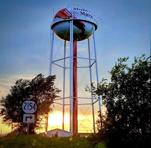 Maker’s Mark water tower stands above a road sign for route 2154 at sunset.